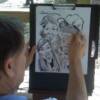 Nick drawing a family's caricature at a company picnic.